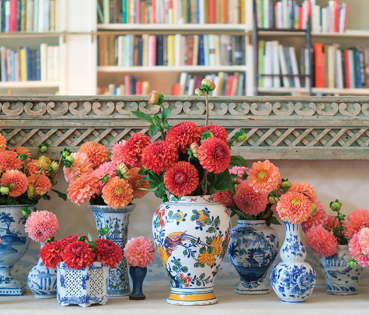 An assortment of blue-and-white chinoiserie vessels filled with dahlia blooms ranging from coral to red