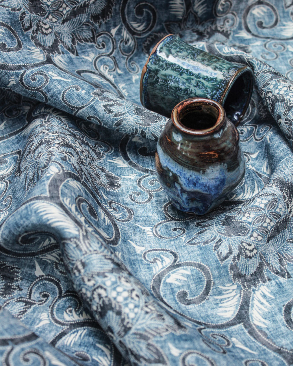 Indigo blue fabric designed by Suzanne Tucker, pictured with blue pottery pieces