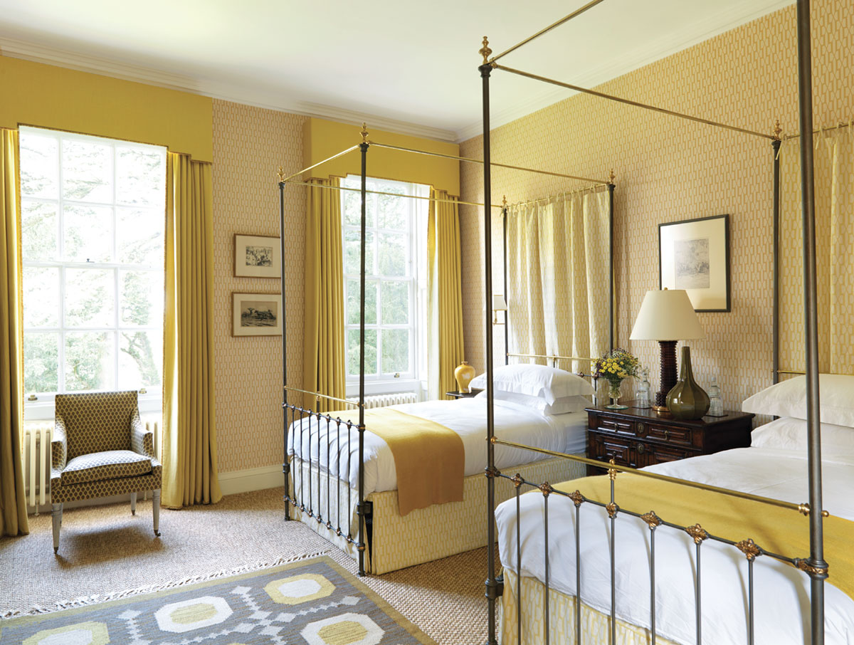 yellow bedroom decorated by Veere Greeney featuring a pair a twin wrought iron canopy beds, and yellow drapes with a tailored valance