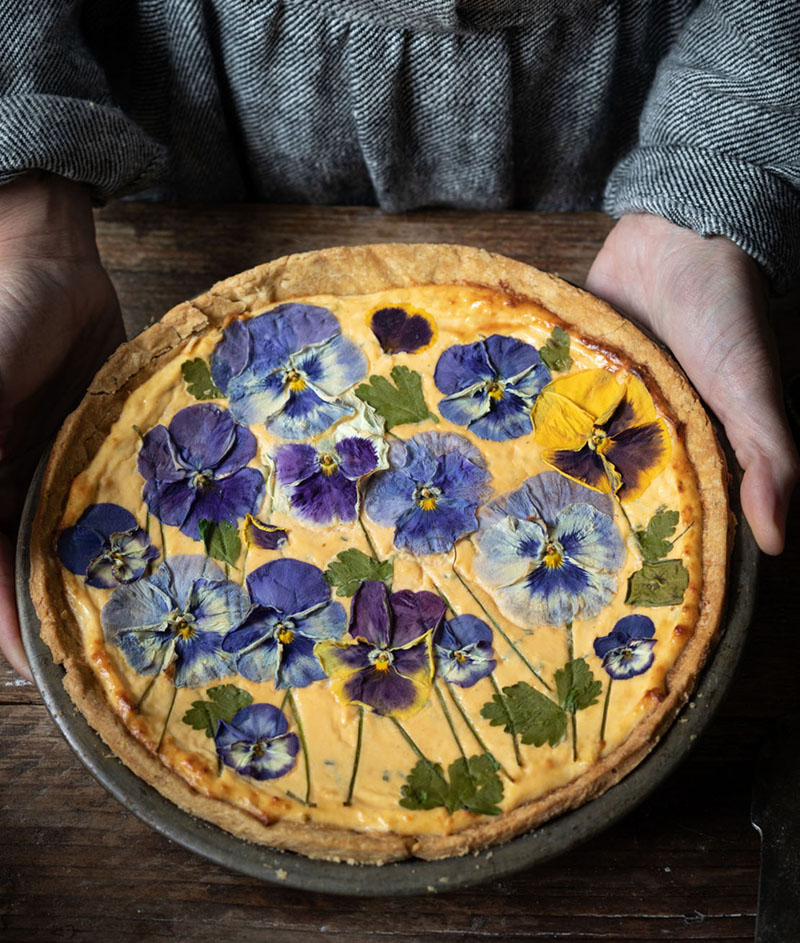 Savory baked cheese tart covered with pressed pansies, an edible flower