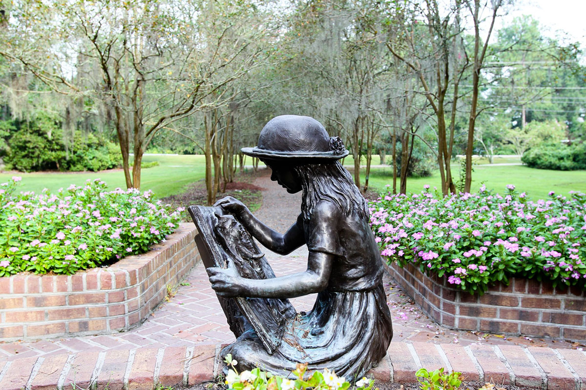 bronze statue of a little girl reading at Azalea Park
