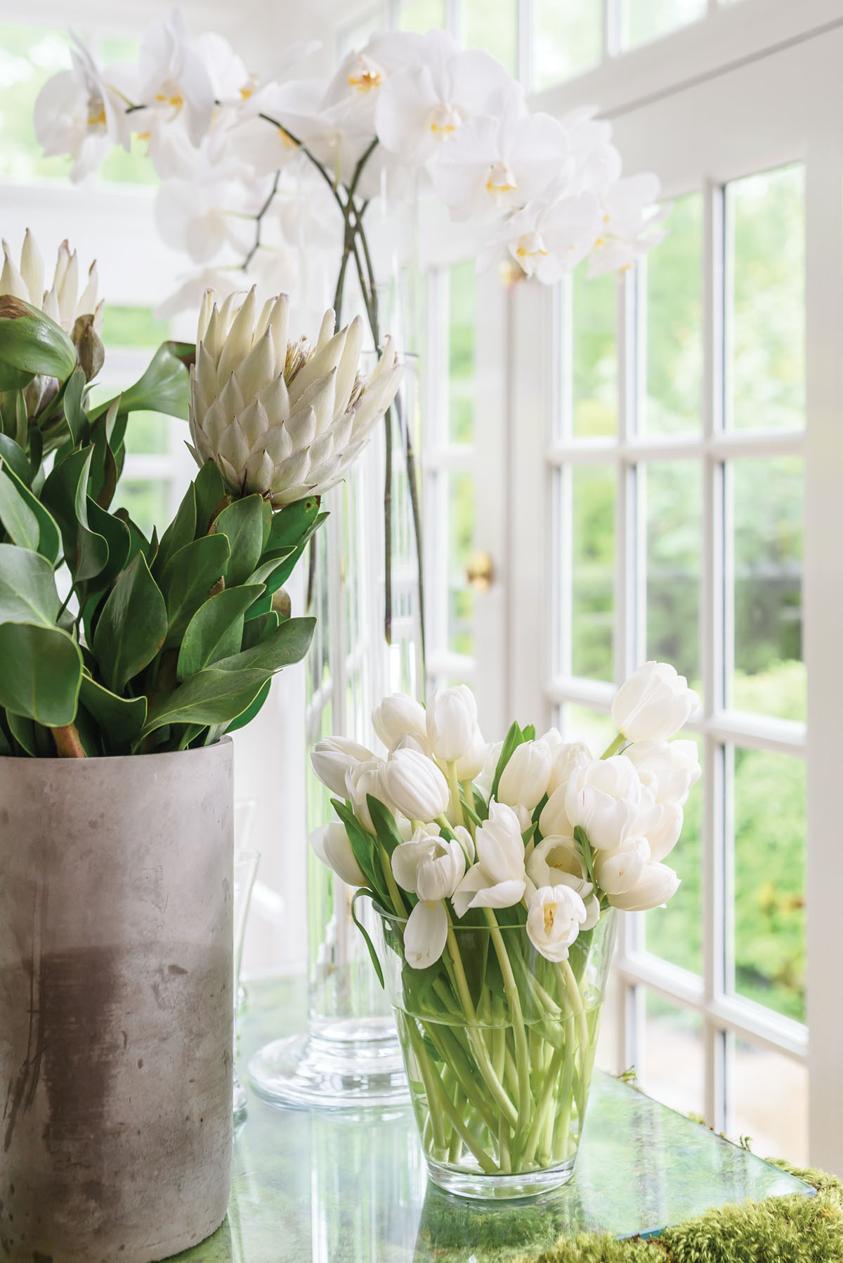 vases of white flowers, arrangement in bunches of a single variety of blooms, including tulips, protea, and orchis