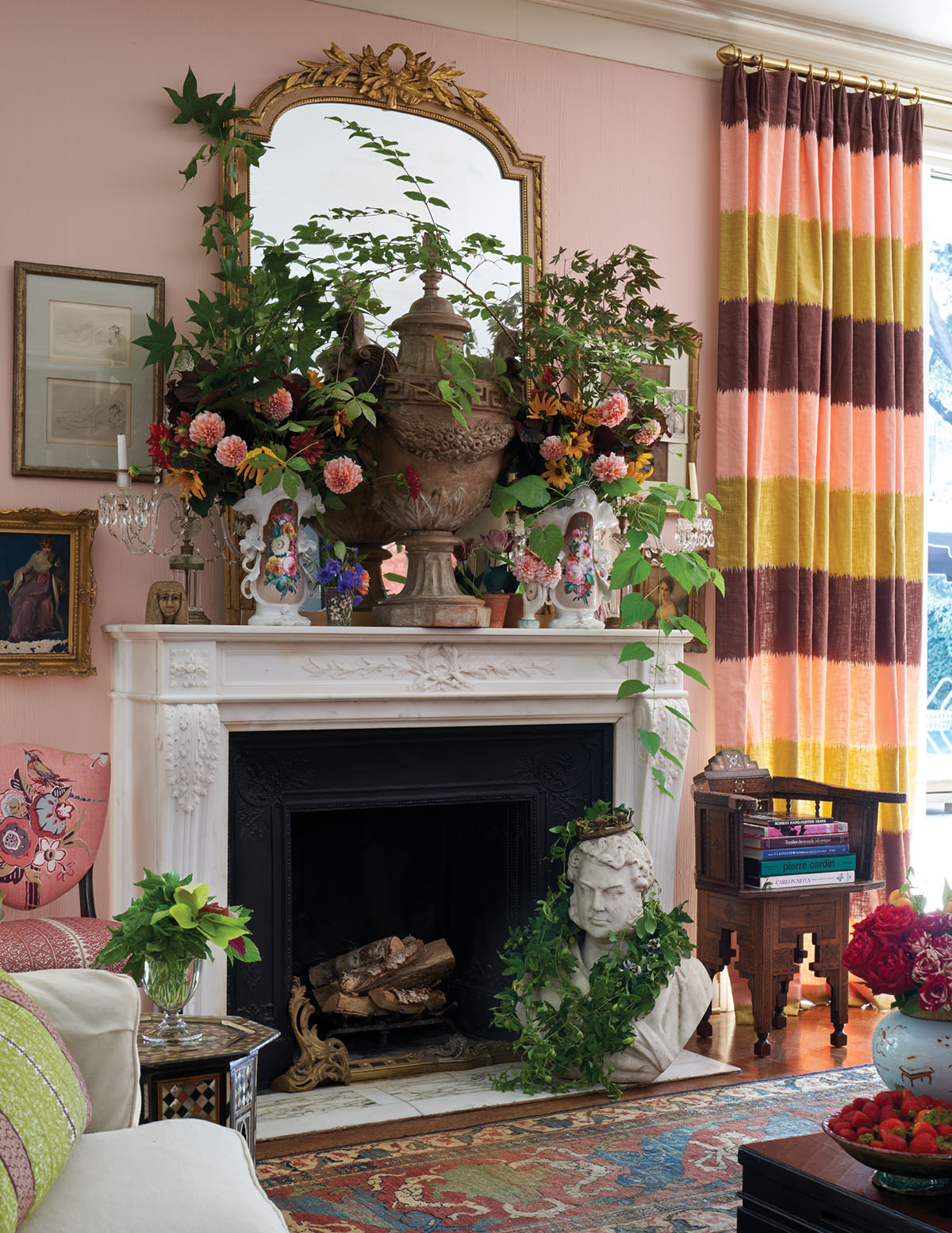 Michelle Nussbaumer’s house, mantel covered in vases of lush floral arrangements, gilt mirror, pink walls, oriental rug, and drapery panels with horizontal strips of pink, green, and chocolate brown