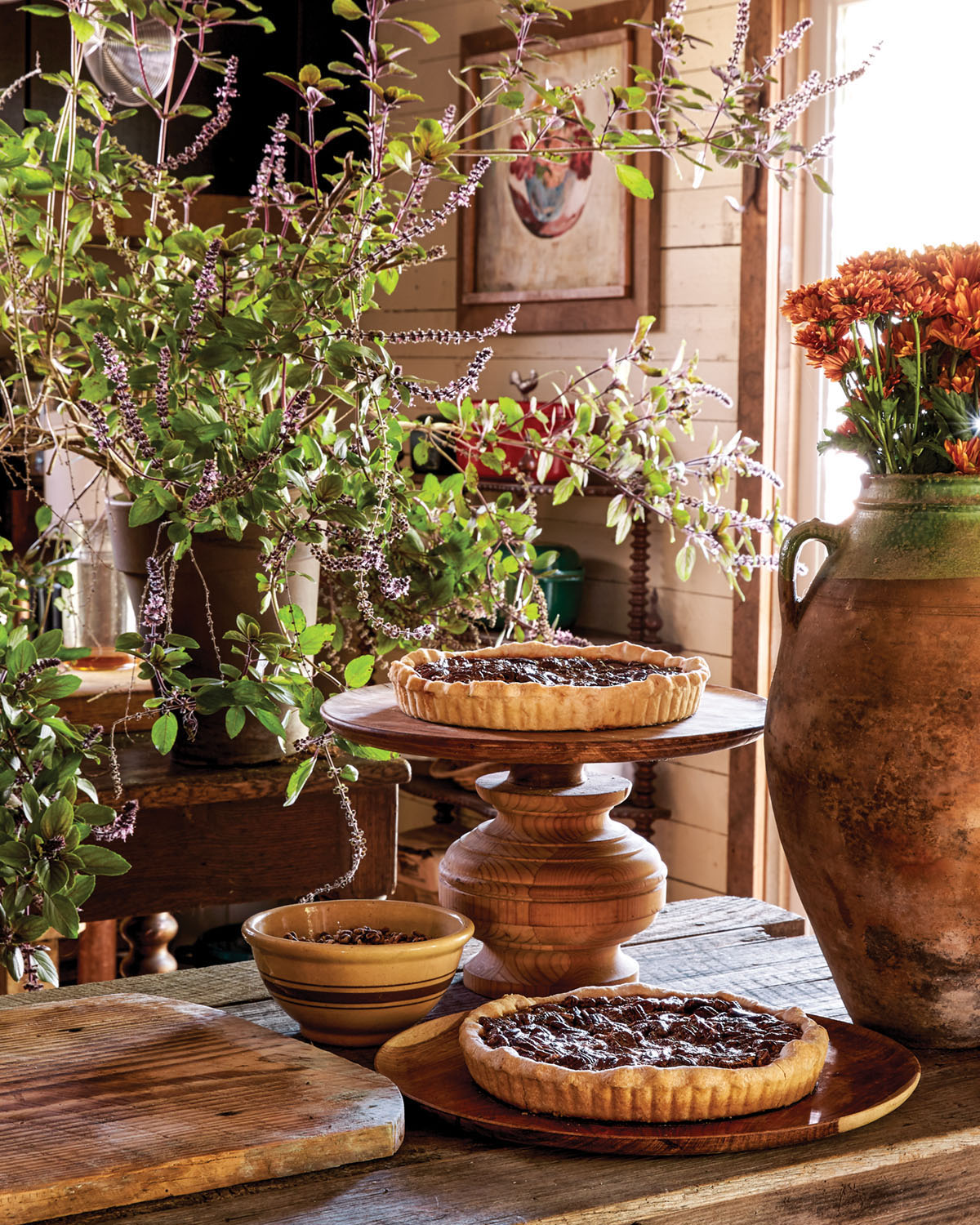 Keith Robinson's fall party spread features a large, wild arrangement of flowering branches, a tall terra cotta pot filled with mums, and rustic fruit pies