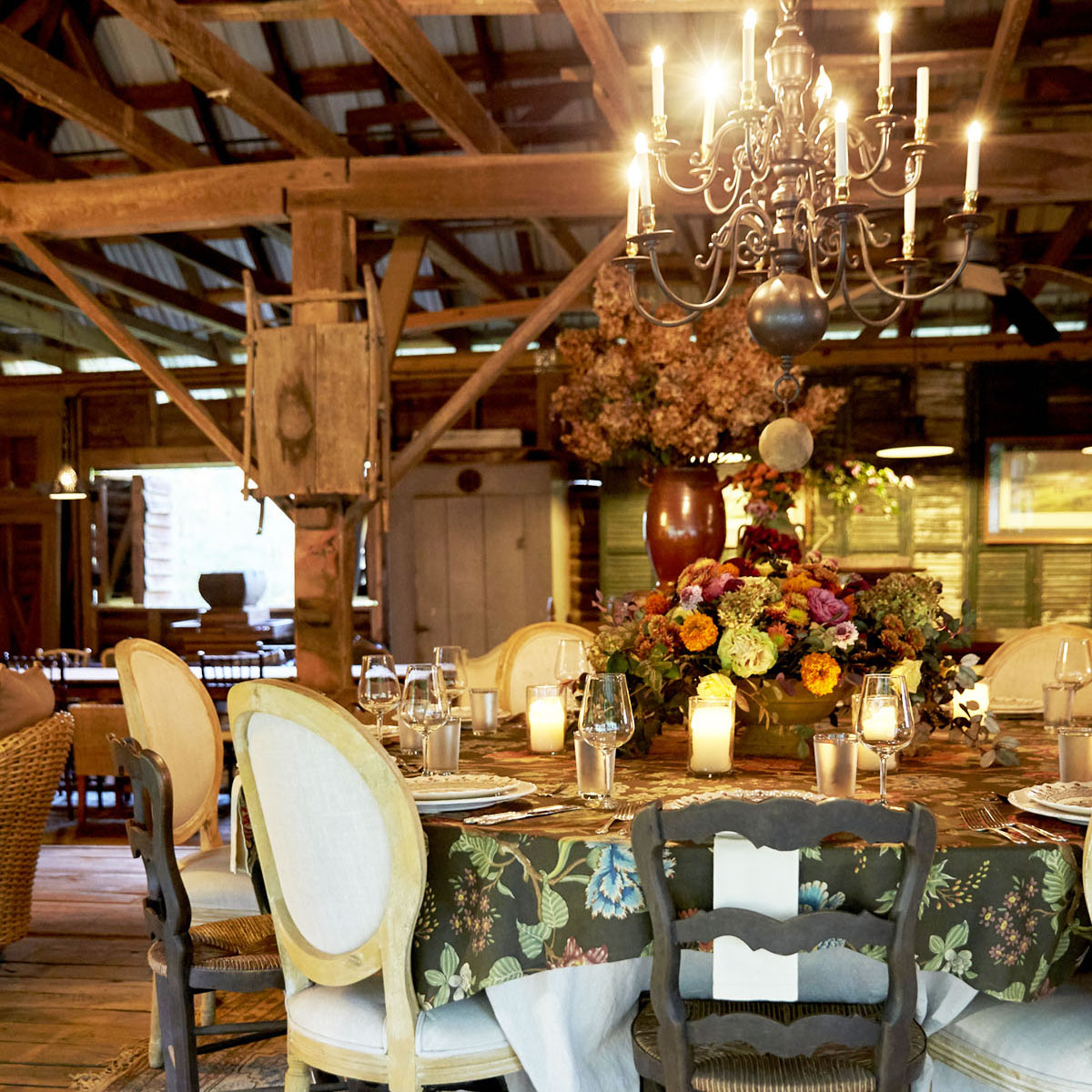 A large display of dried hydrangeas in the background adds seasonal texture inside Keith’s rustic entertaining pavilion. a fresh arrangement sits on the table for a gathering.