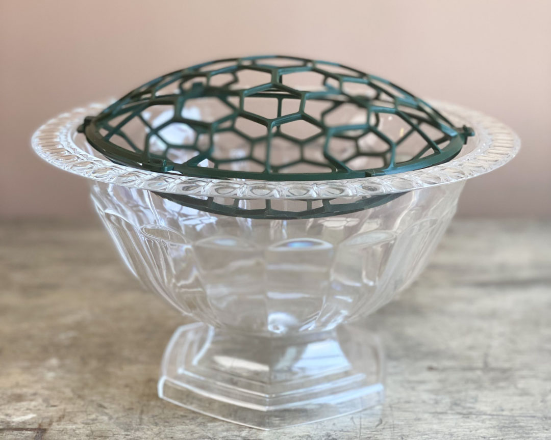 Clear glass compote holding a Holly Pillow floral mechanic. 
