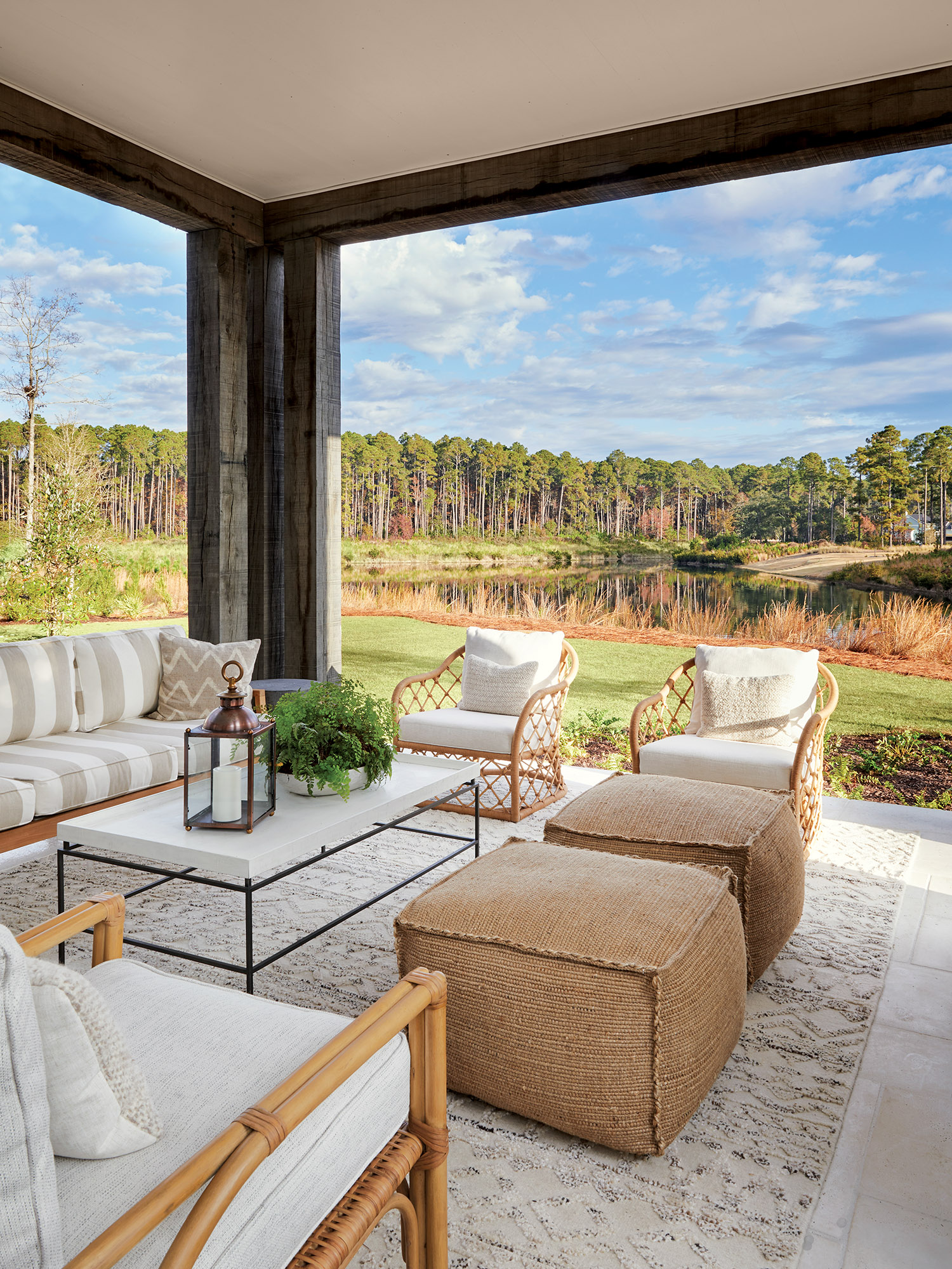 A porch decorated in linen furniture overlooks a marsh.