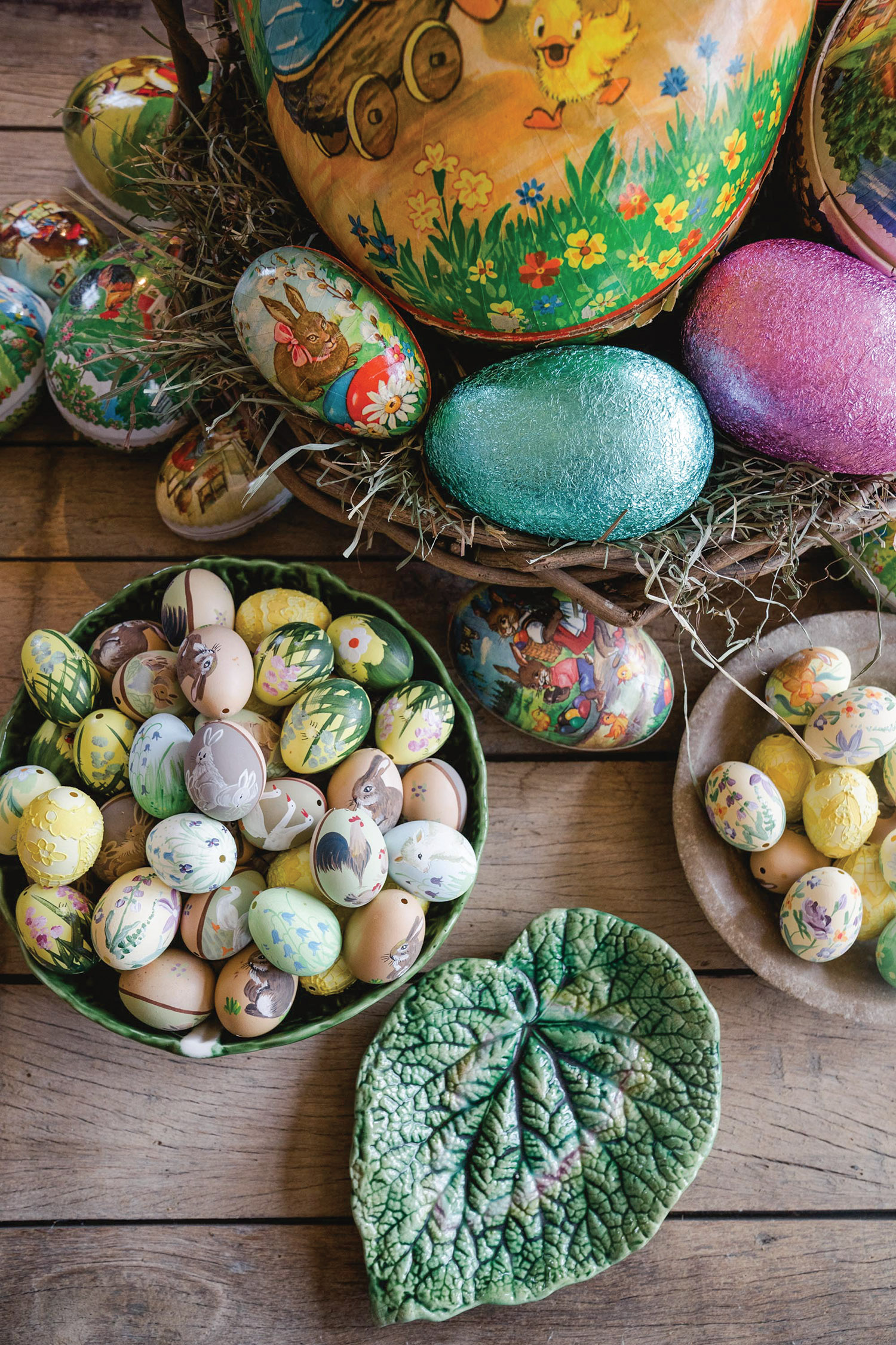 Painted easter eggs lay in a basket on a table.