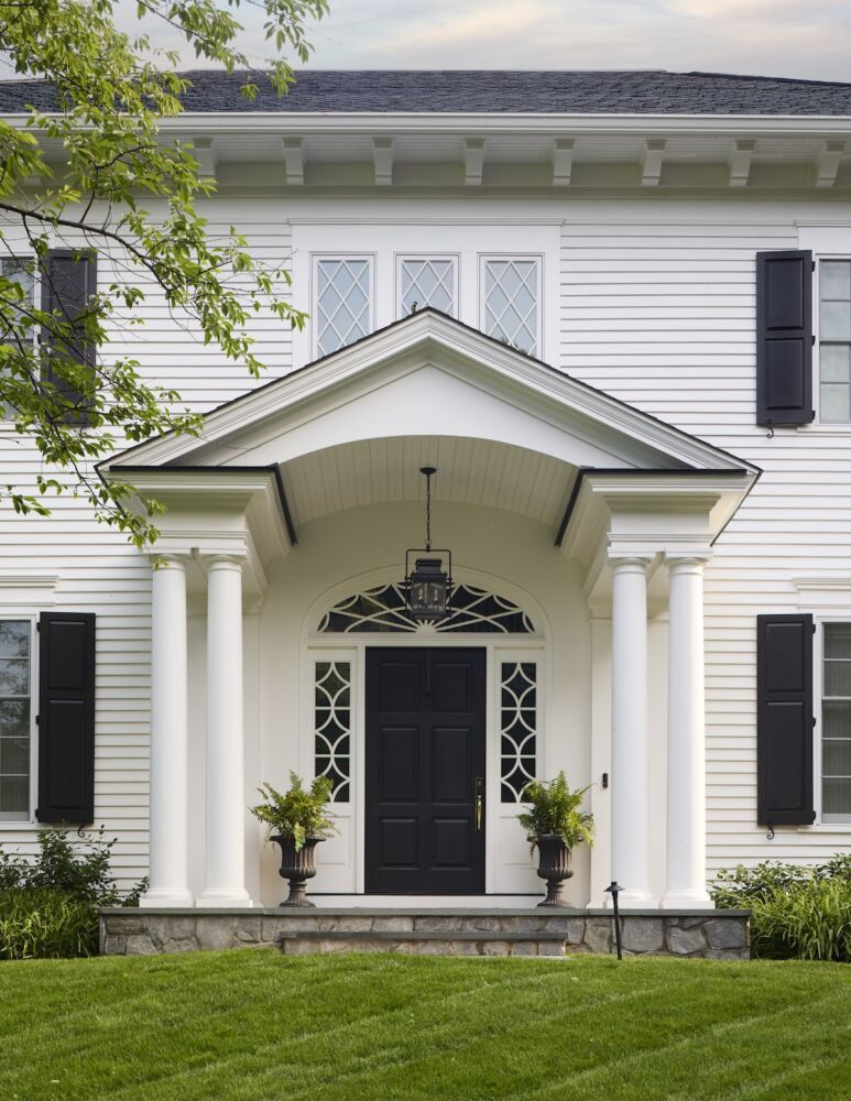 Facade of a Colonial Revival style with classic columns, pediment, and windows, white façade with black accents