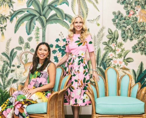 Roxy Owens and Sarah Wetenhall are side by side in front of a tropical mural. They worked on the colony hotel renovation.