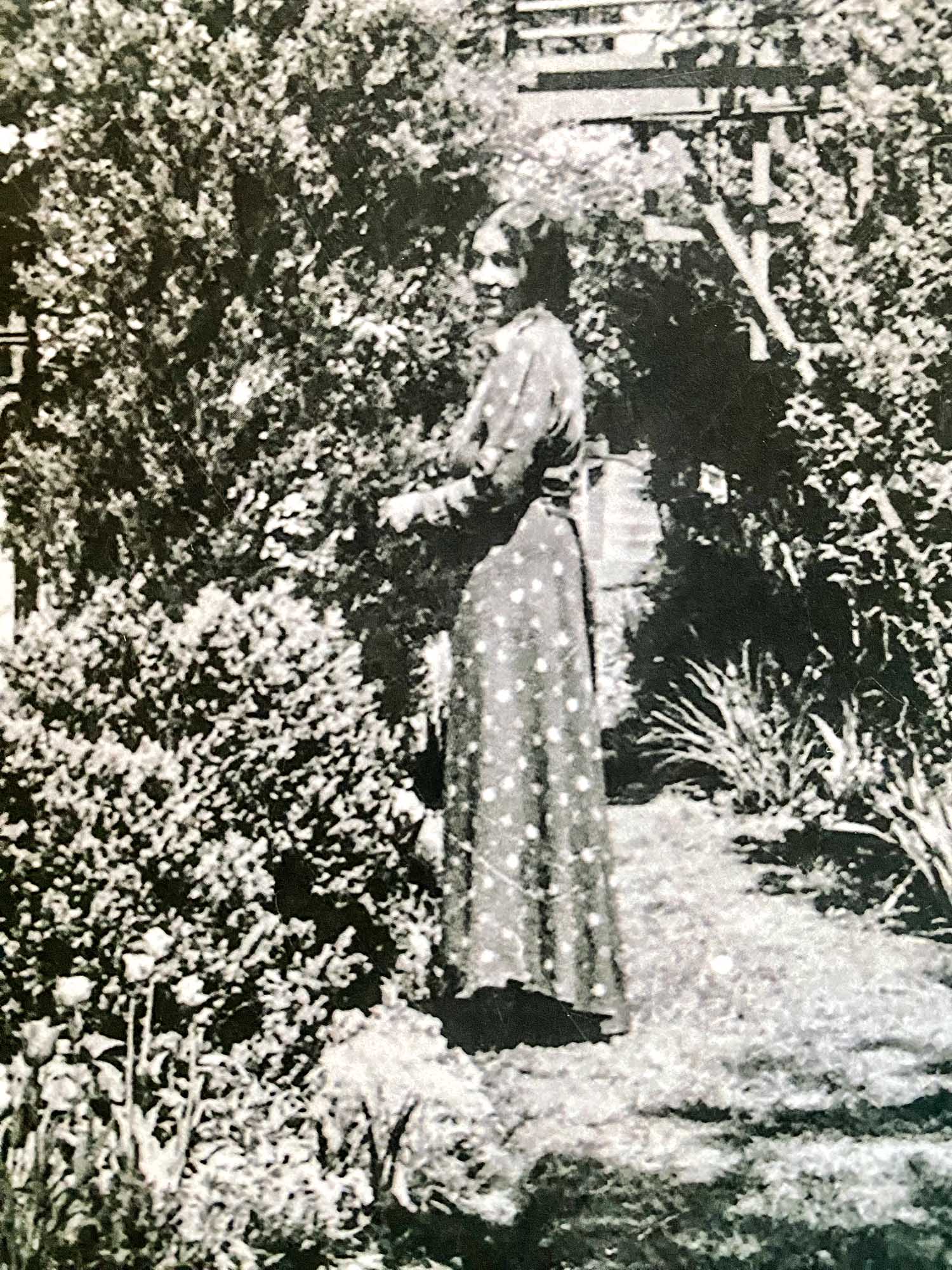 Anne Spencer walks through her garden in a polka dot dress in a black and white photo.