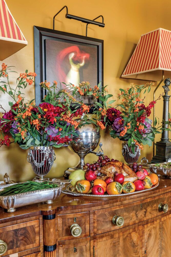 A wooden hutch holds fruits and flowers nexts to red striped lamps.