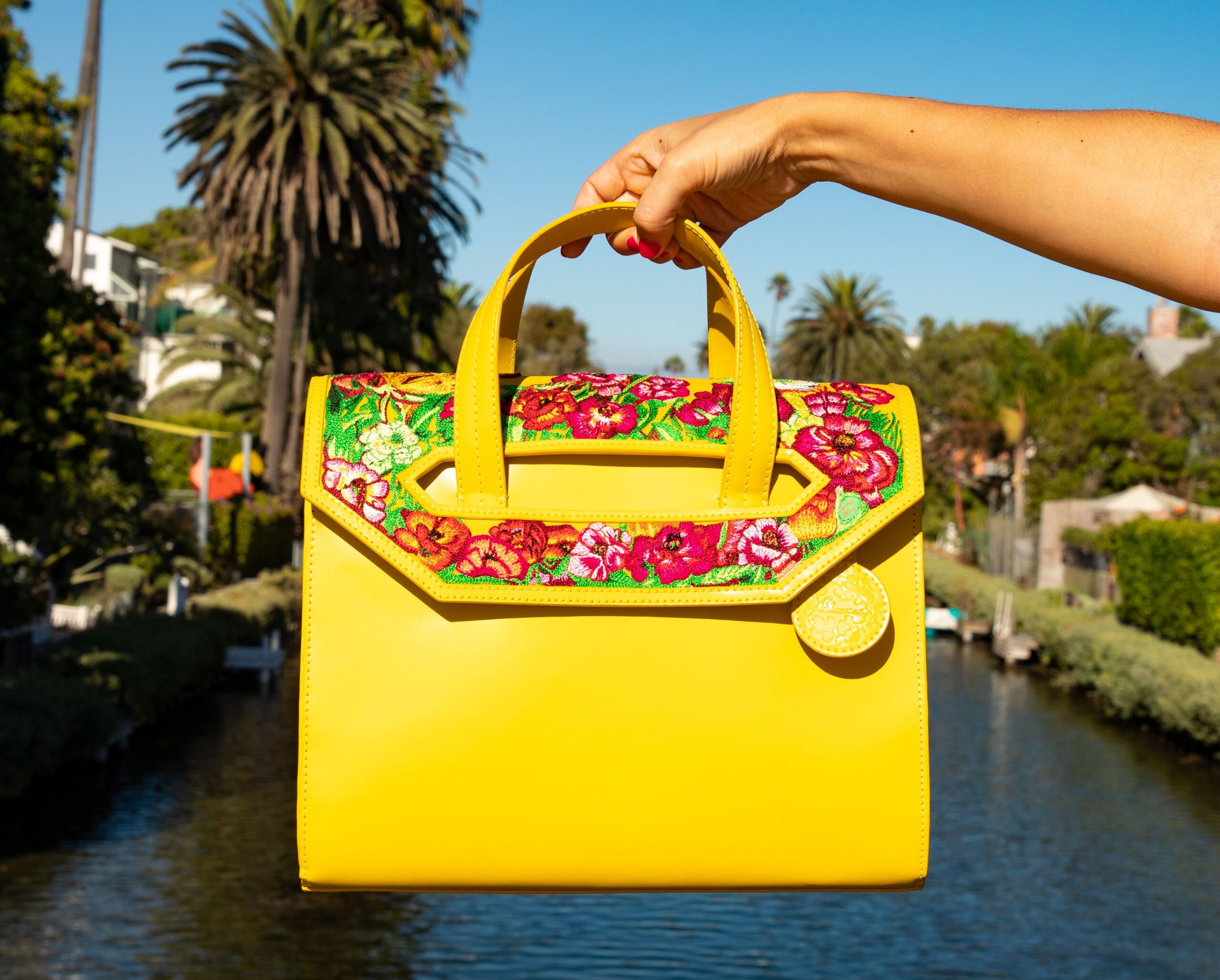 A bright yellow bag has embroidered pink poppies on it.