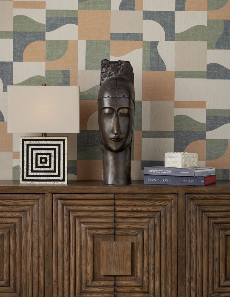 Large bust, graphic black and white square lamp, stack of books and a box atop a wooden chest or credenza.