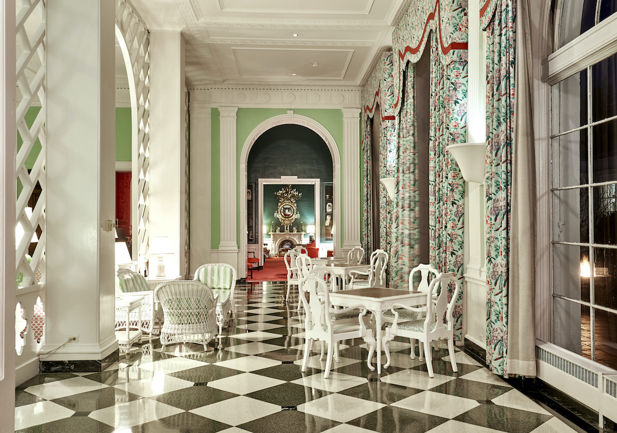 A black checkerboard dining room with green drapes and walls, decorated by Dorothy Draper at the Greenbrier.