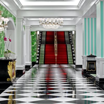 The Greenbrier Avenue staircase carpeted in red and green with black borders. Black and white tiled floor foreground.