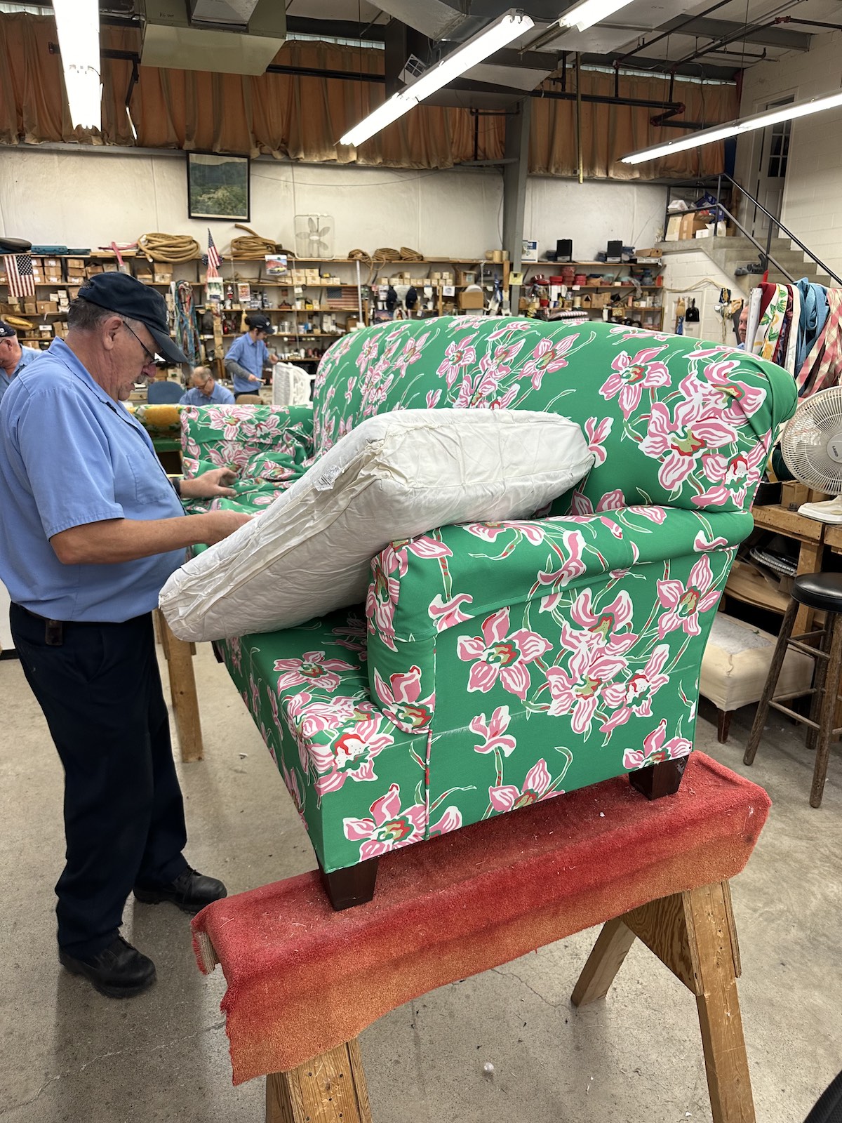 Man reupholsters a couch in floral cloth.