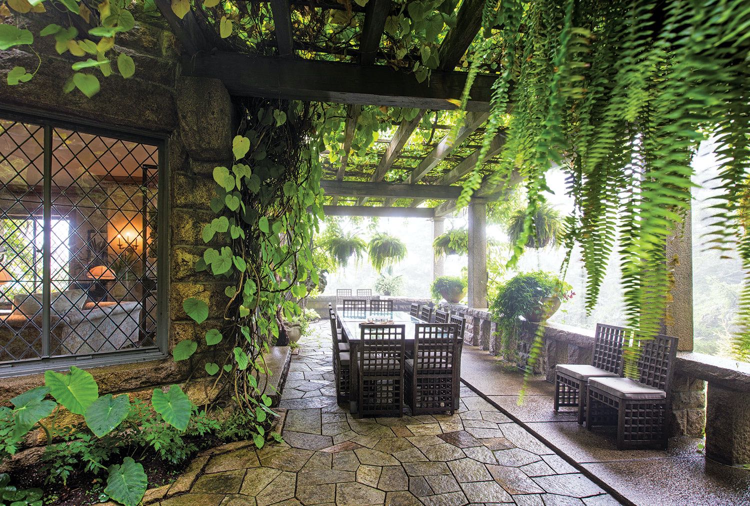 Shaded, stone-floored dining terrace surrounded by ferns and vine-covered walls at Skylands, Martha Stewart's summer home in Maine. 