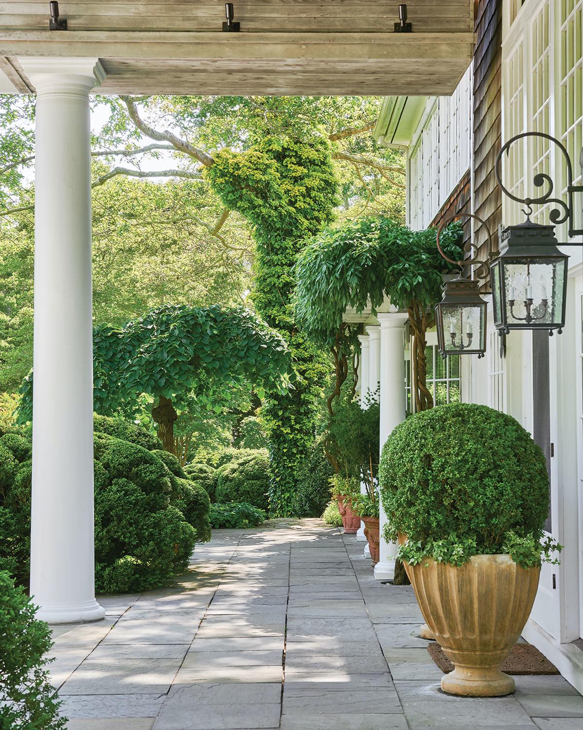On the terrace, urns of boxwood flank the door to the living room.