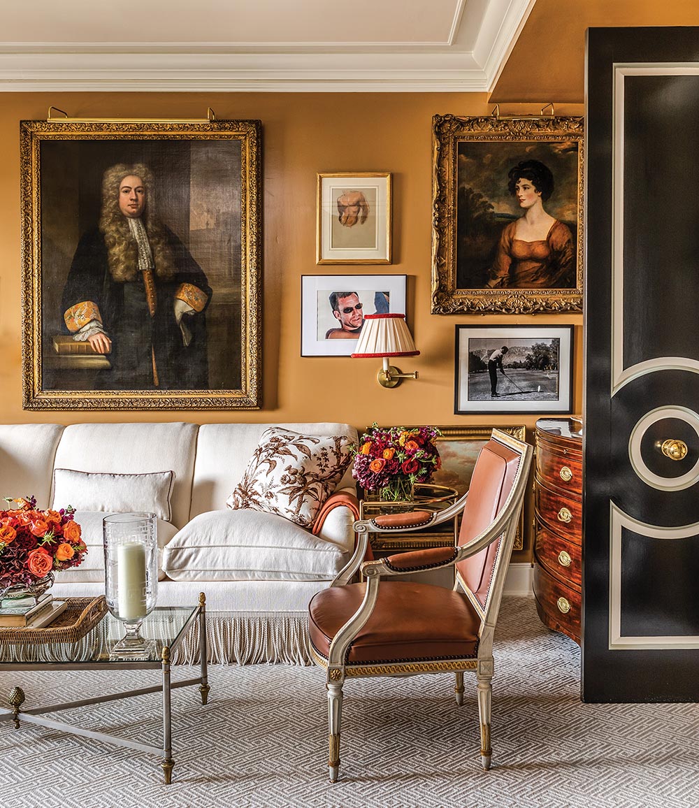 A gold painted living room has photographs and portraits on the wall.