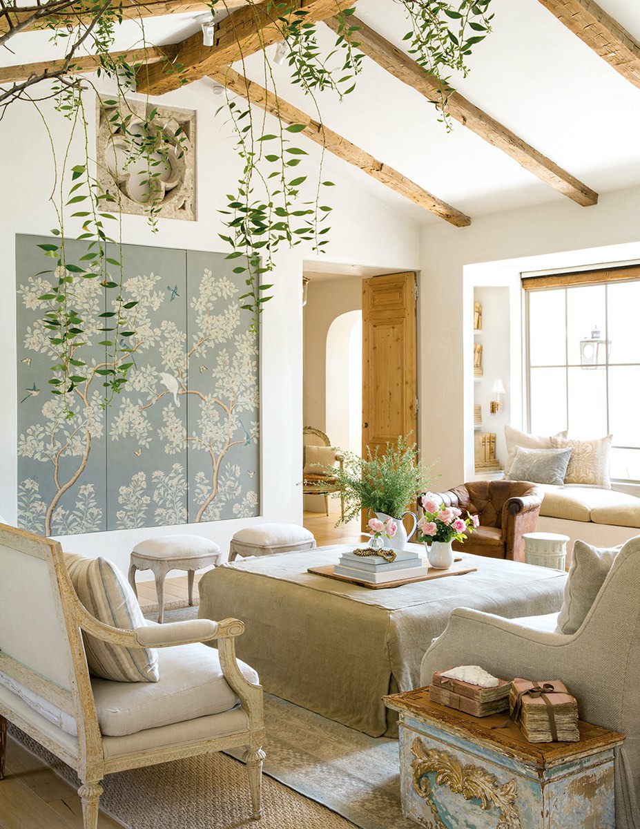 Weathered wood beams and doors mingle with formal elements such as Gracie wallpaper panels that conceal a television.