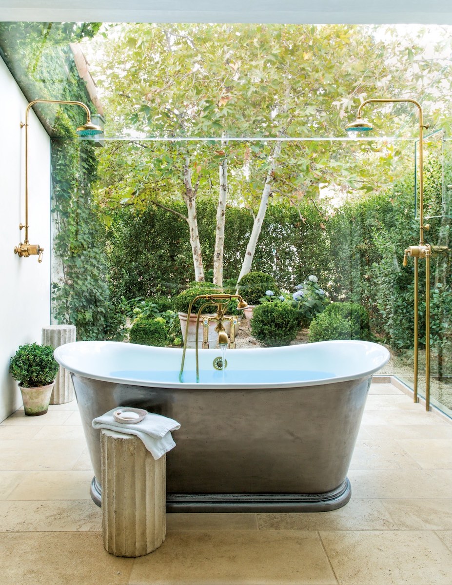 A glass wall and ceiling in the master bath appear to extend the room right into the garden. A dense hedge provides plenty of privacy.