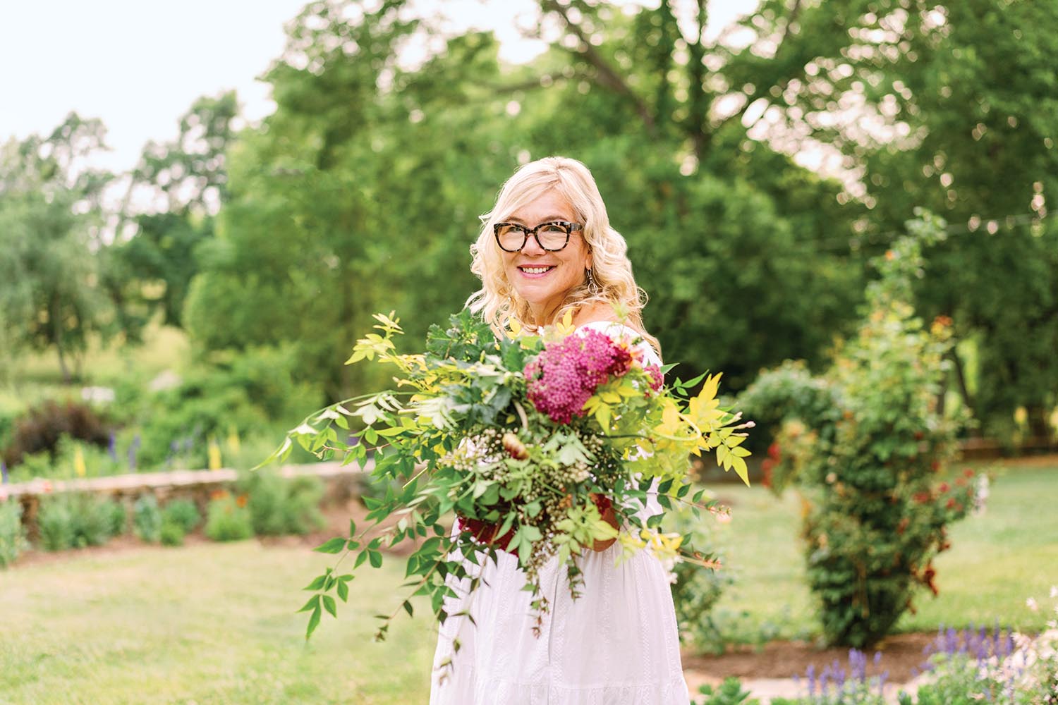 Holly Chapple holds bunches of flowers in a field.