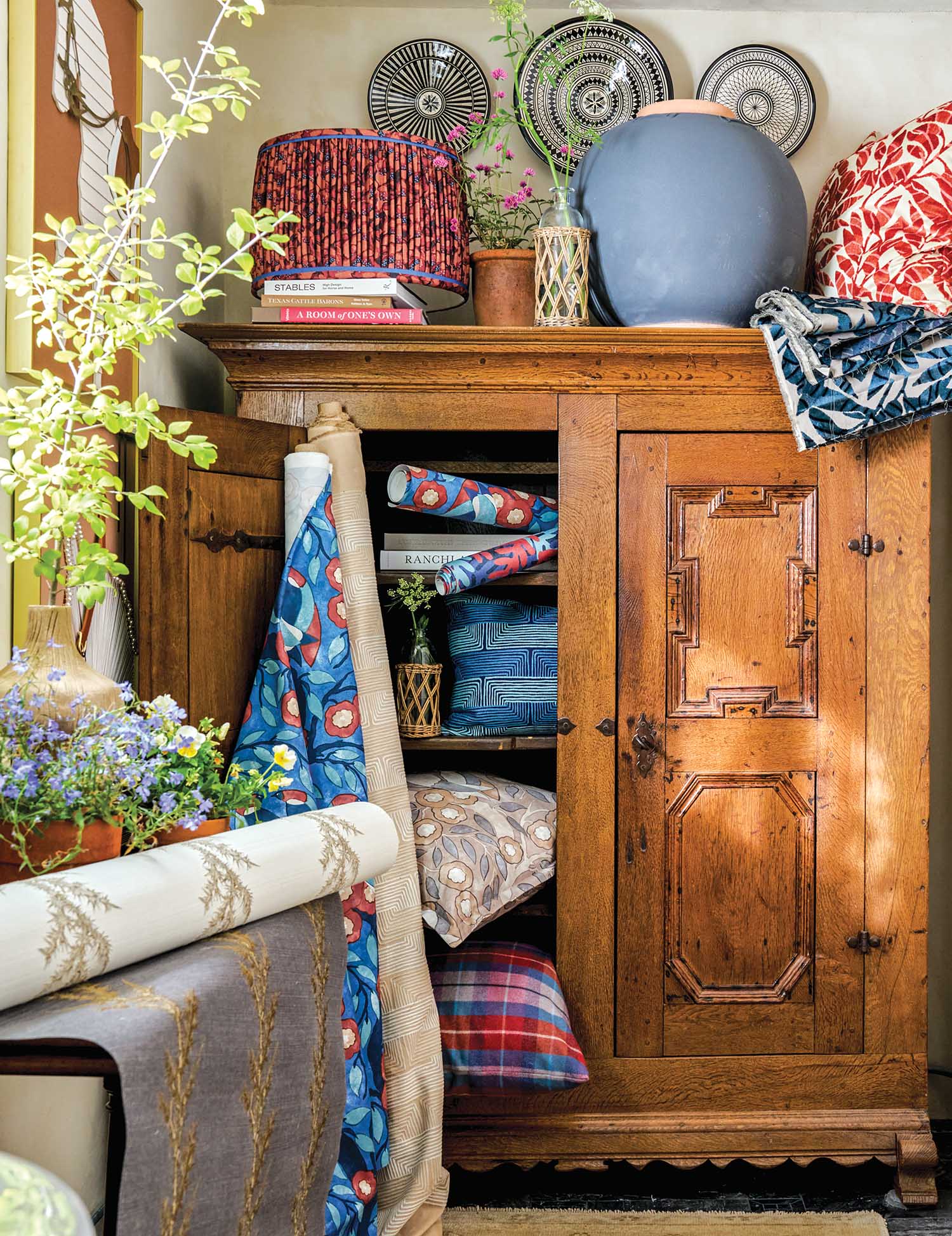 Fabrics, pillows, and lampshades are around a wooden cabinet.