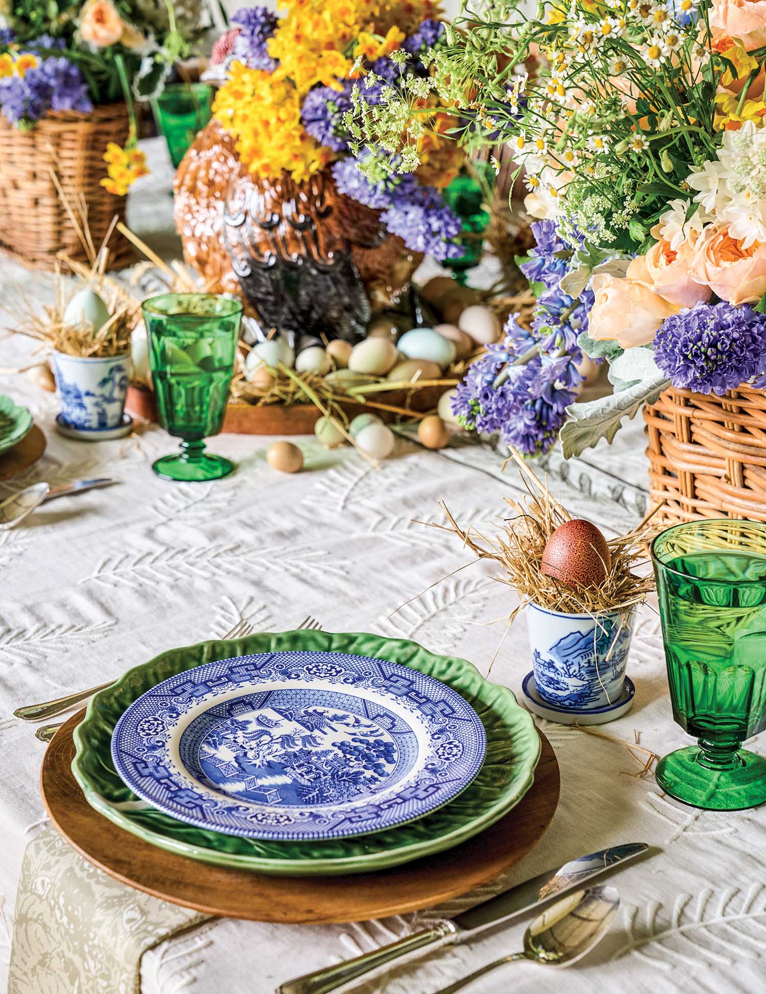 A blue plate is set at a table with spring flowers.