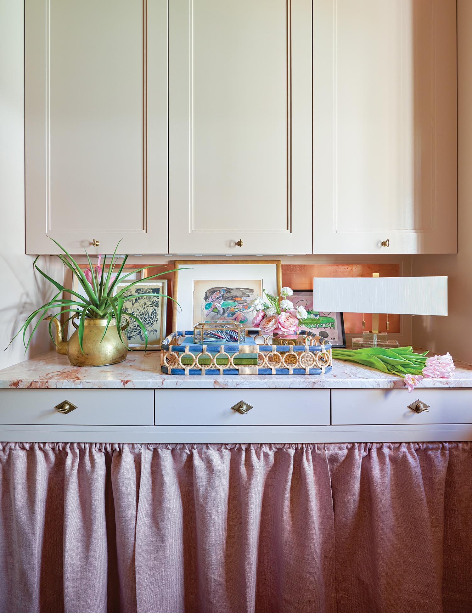 A laundry room has cream cabinets with linen curtains at the bottom.