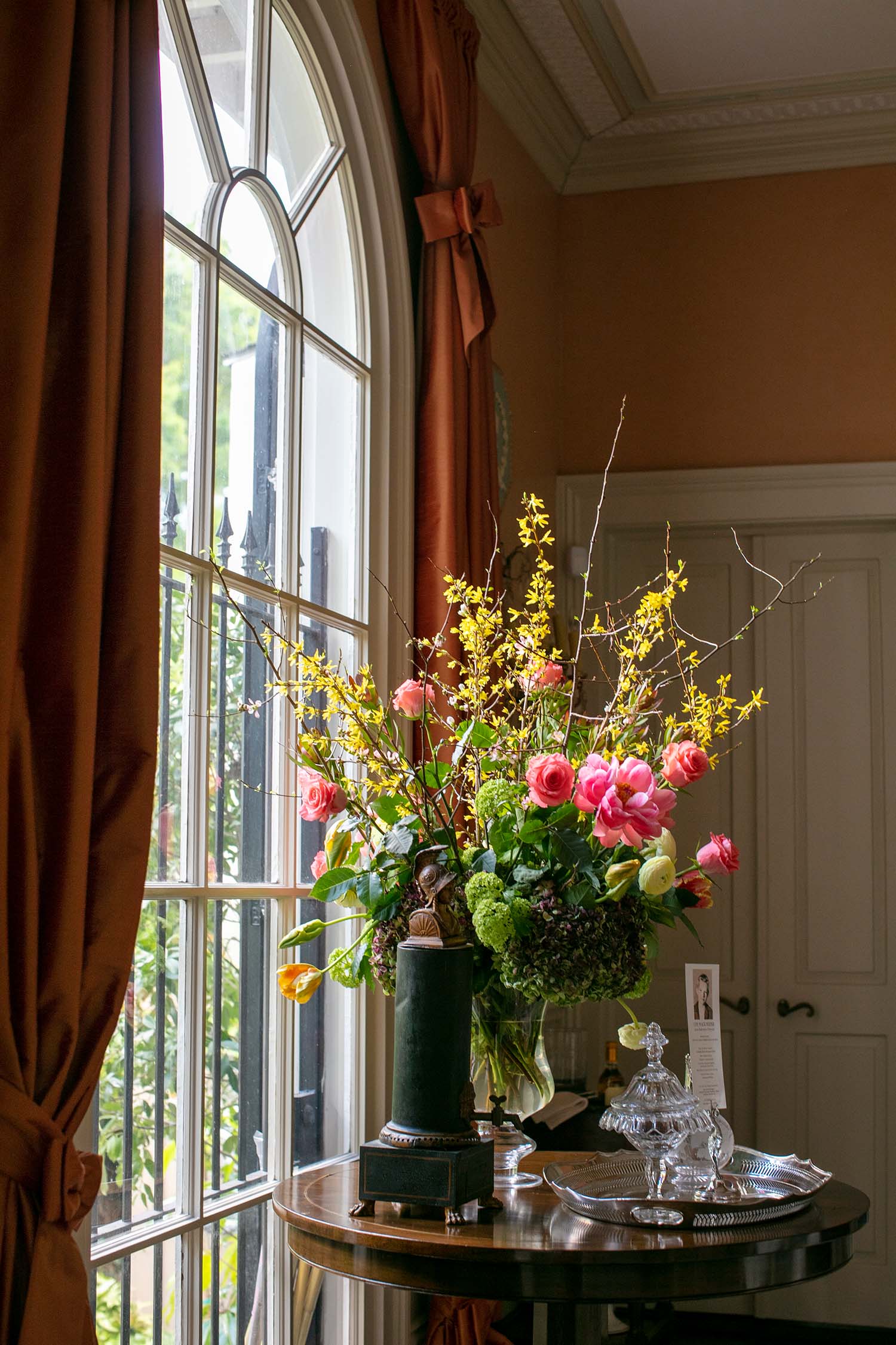 Peonies and forsythia in an arrangement near a window.