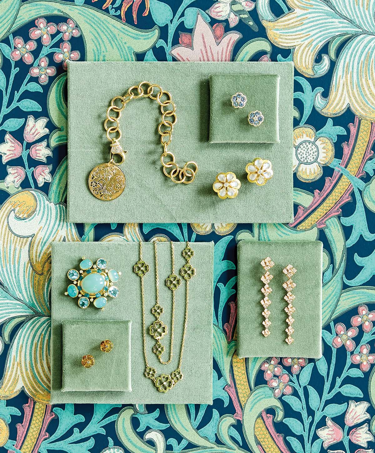 Pieces of jewelry styled on top of floral wallpaper.