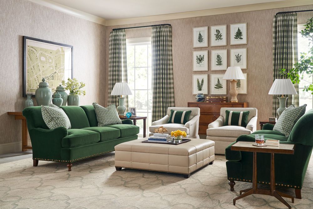 Living area with pair of green sofas on either side of a low, leather ottoman.