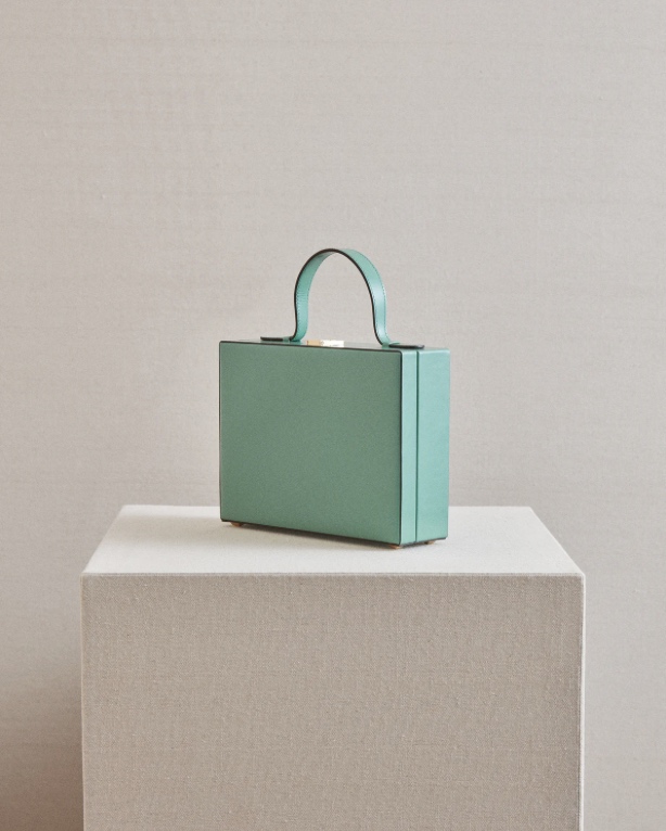 A small teal blue bag sits on a stand.