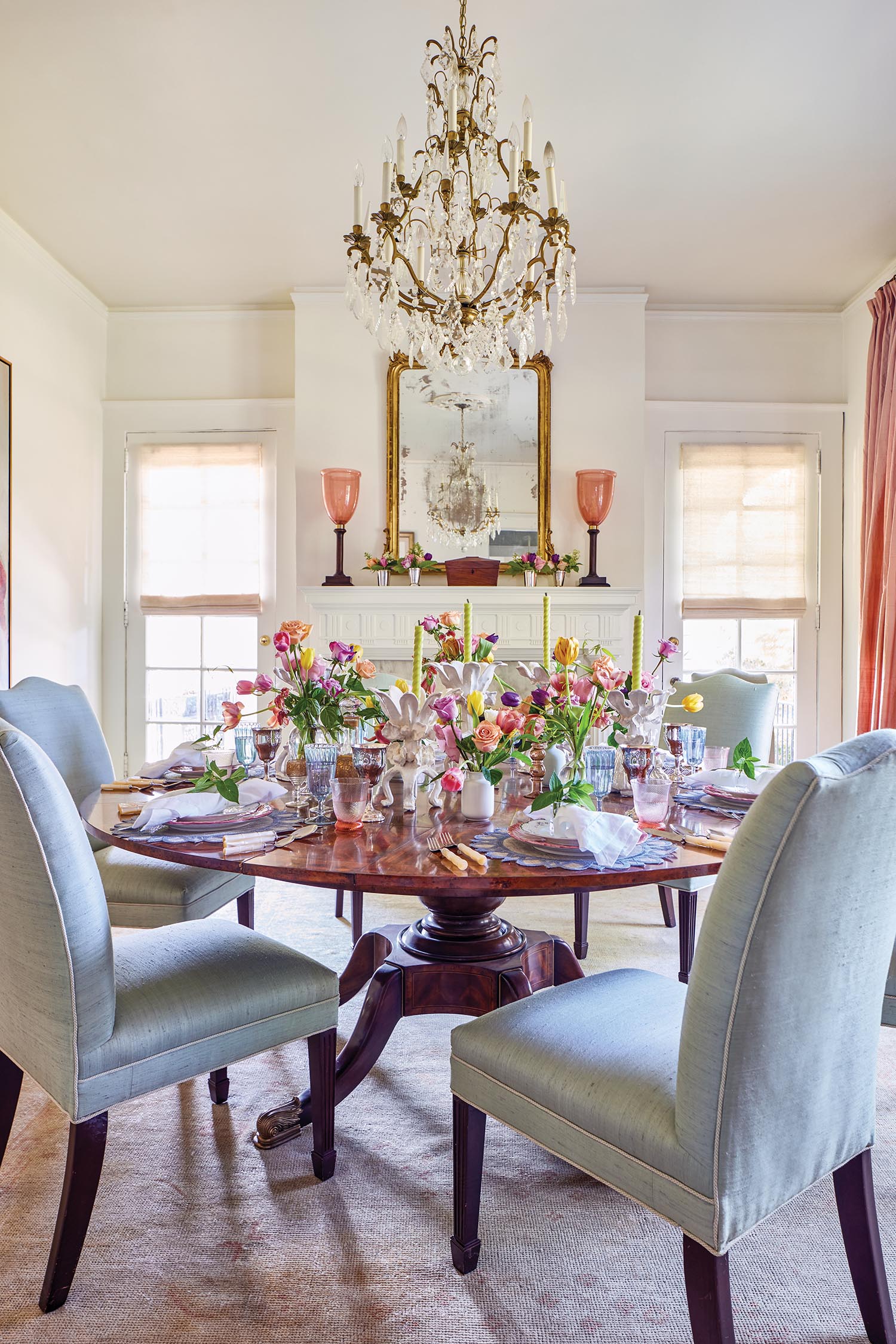 A dining table is set with flowers and surround by light blue chairs.