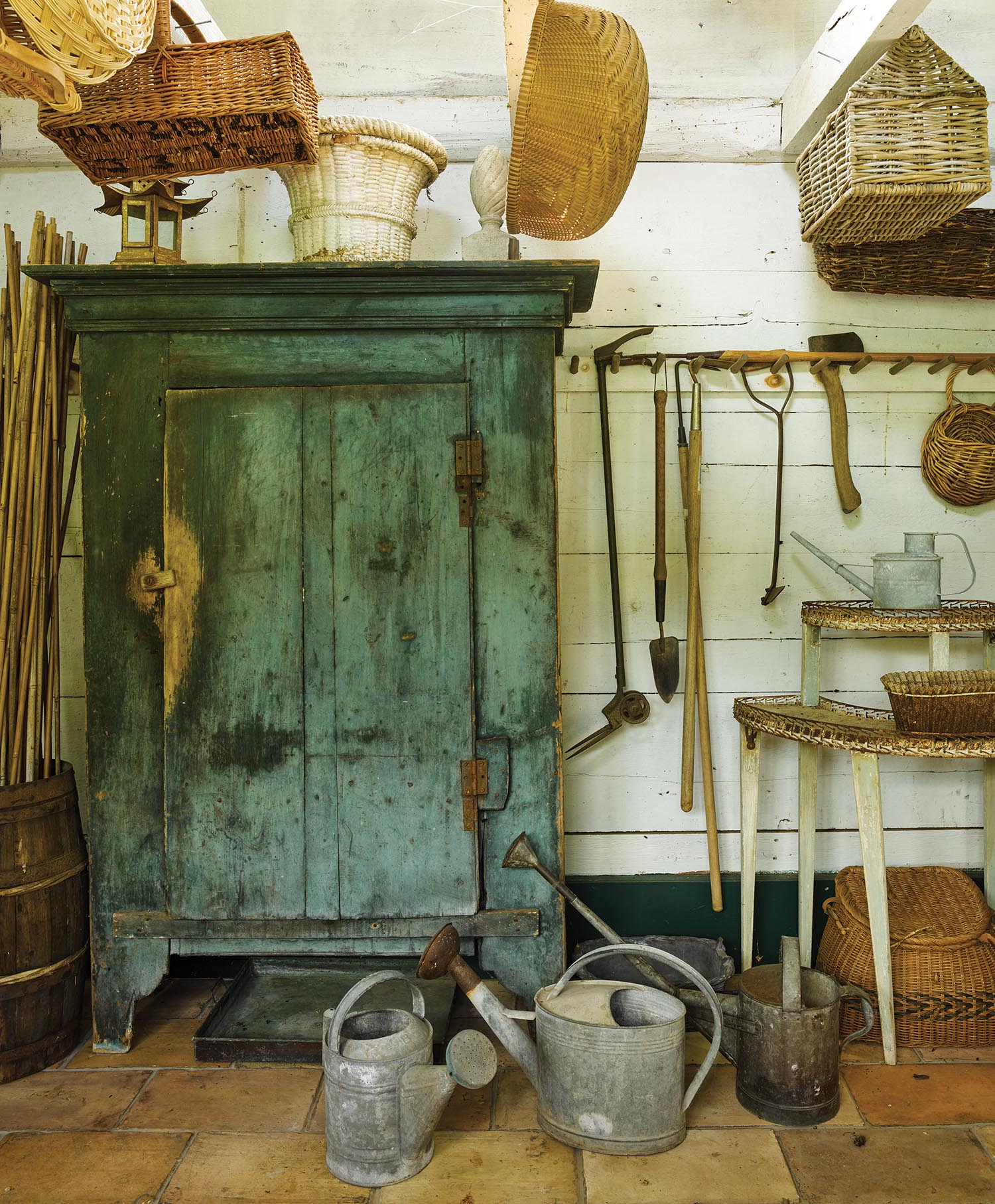 A blue cabinet sits among watering cans.