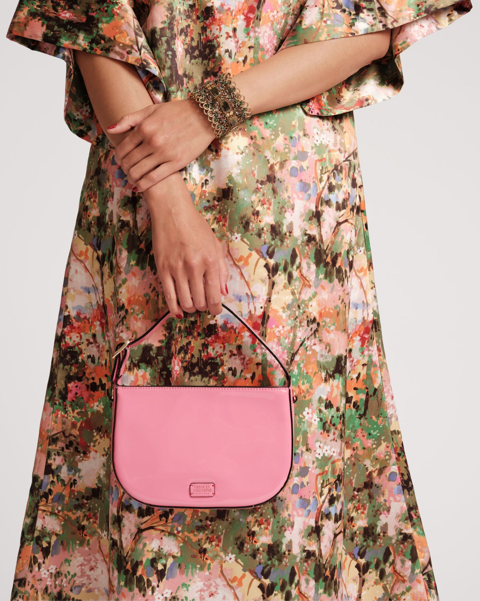 Woman in patterned dress holding a small pink bag.