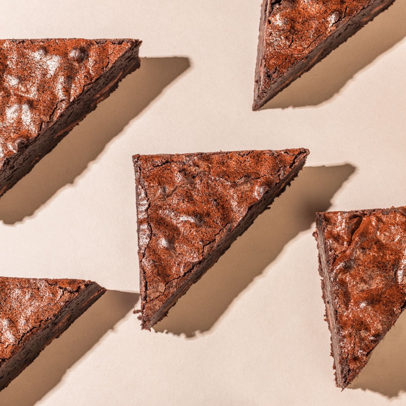 Triangle brownies laid out on pink paper.