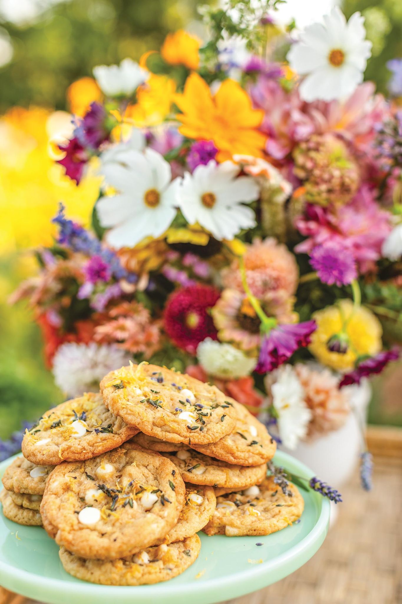 White chocolate chip cookies with lavender sprinkles in front of vase of summer flowers