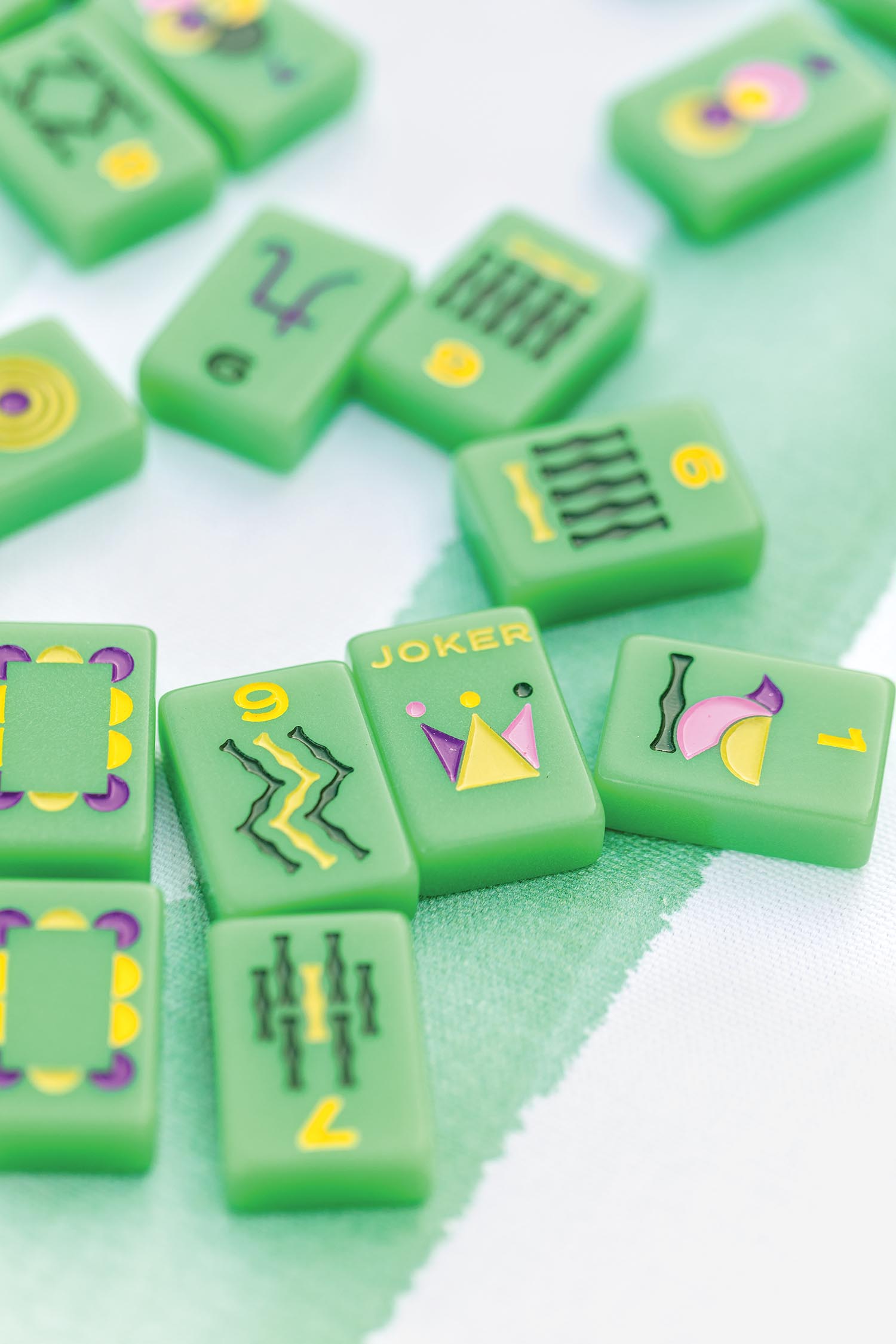 Green Mahjong tiles scattered over a striped tablecloth.