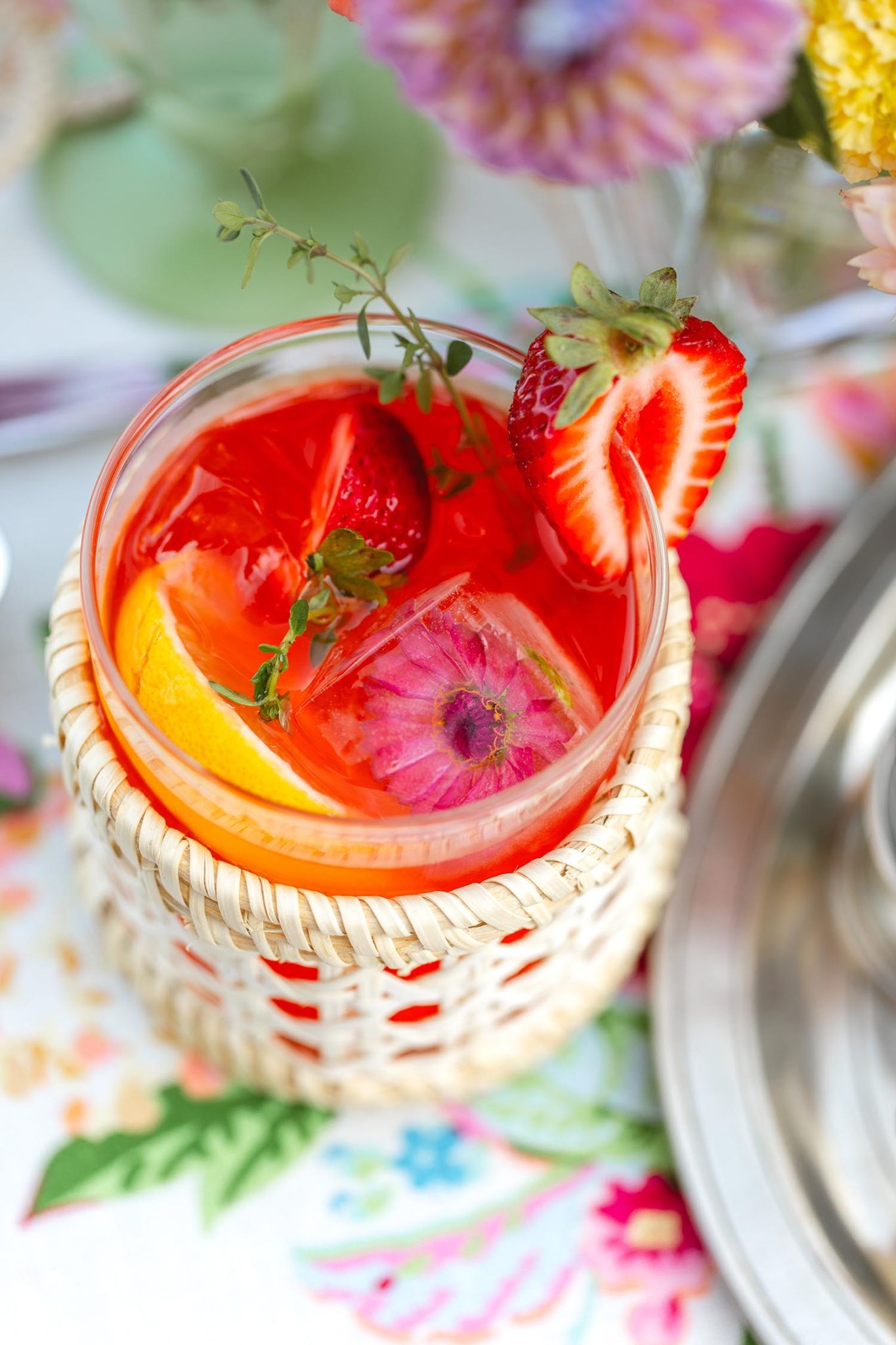 A closeup of a cup with floral ice cubes and a strawberry lemonade drink.