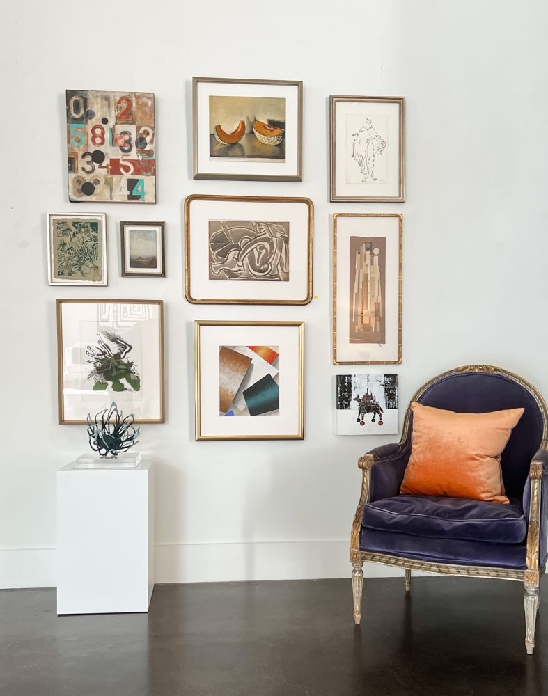 A gallery wall accented by a blue velvet chair.