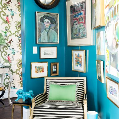 A bright teal room has a corner decked out in a gallery wall.