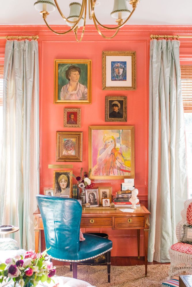Colorful portraits of women create a gallery wall in a peach colored room.