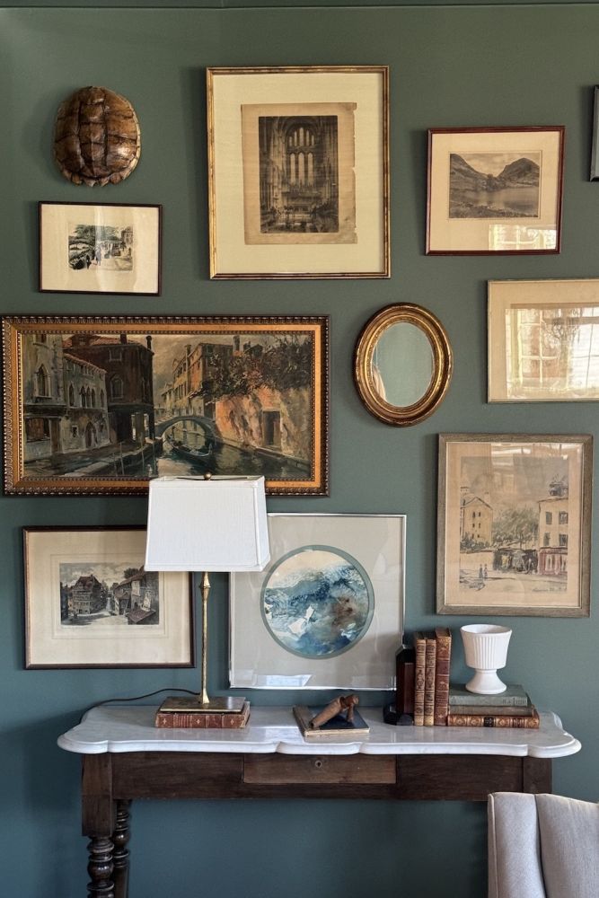 A gallery wall of antique prints on a green background.
